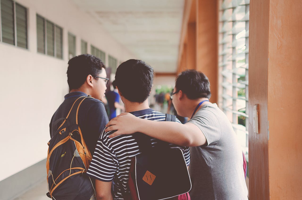 services-02 Group of male teenagers walking in a school corridor with backpacks, bonding and chatting.
